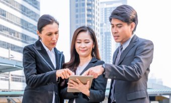Group of professionals discussing something detailed on the tablet
