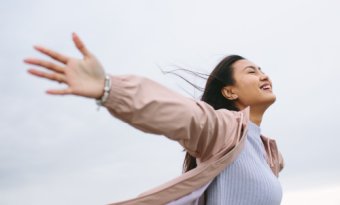 A woman outside posing with arms wide open